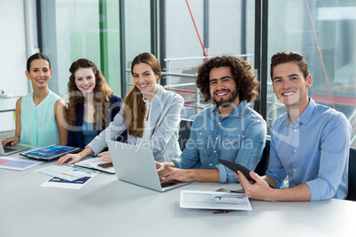 Smiling business team working on laptop and digital tablet in meeting Smiling business team working on laptop and digital tablet in meeting