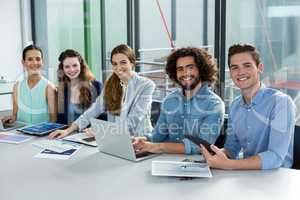 Smiling business team working on laptop and digital tablet in meeting