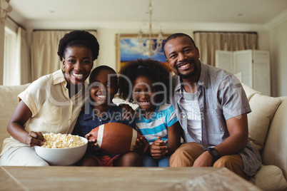 Portrait of parents and kids watching television in living room
