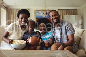 Portrait of parents and kids watching television in living room