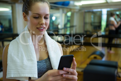 Beautiful fit woman using mobile phone after workout