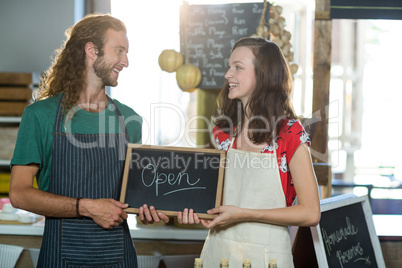 shop assistants holding open sign board
