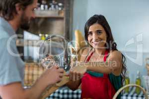 Portrait of smiling bakery staff giving parcel to male customer at counter