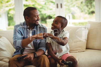 Father and son fist bumping while playing video game