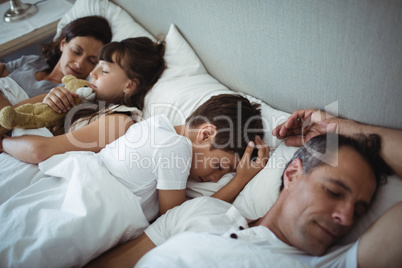 Parents and kids sleeping on bed