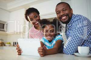Portrait of parents and daughter using digital tablet in kitchen