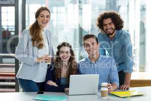 Portrait of smiling business team working on laptop in meeting