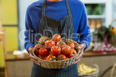 Vendor holding a basket of tomatoes