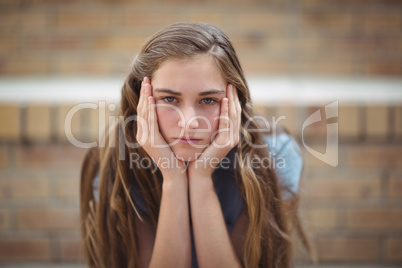 Portrait of sad schoolgirl sitting alone in campus