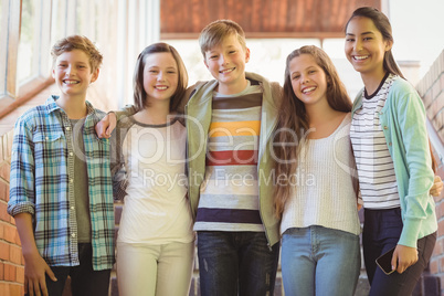 Portrait of happy students standing with arms around in corridor