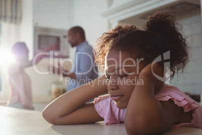 Sad girl fed up of her parents arguing in kitchen