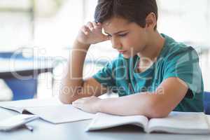 Attentive schoolboy studying in classroom