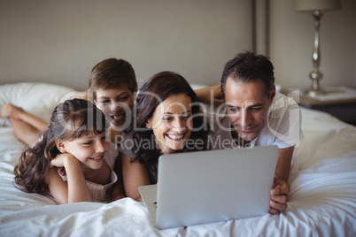 Happy family using laptop on bed in bedroom