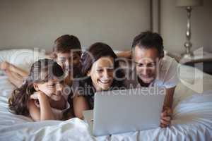 Happy family using laptop on bed in bedroom