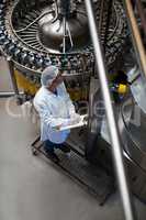 Factory engineer monitoring filled juice bottle on production line