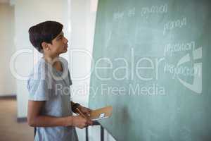 Attentive schoolboy reading chalkboard in classroom