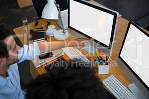 Man and coworker discussing over desktop pc