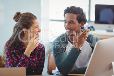 Male and female graphic designers interacting with each other at desk