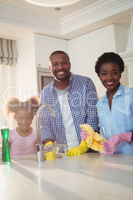 Portrait of family washing utensils in kitchen sink
