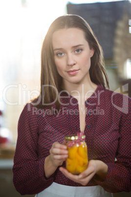 Shop assistant holding a jar of pickle in grocery shop