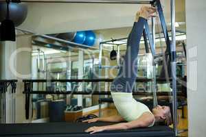 Determined woman performing stretching exercise on reformer