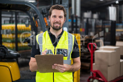 Factory worker writing on clipboard in factory