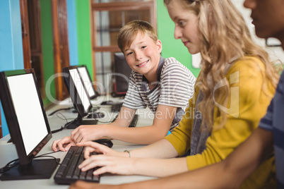 Smiling students studying in computer classroom