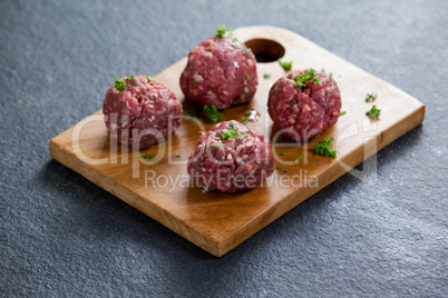 Minced beef garnished with coriander leaves on wooden board