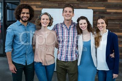 Smiling business executives standing together with arm around in office