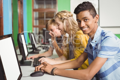 Smiling students studying in computer classroom