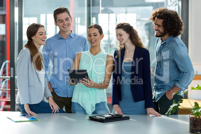 Smiling business team discussing over digital tablet in meeting