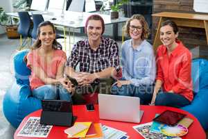 Smiling graphic designers sitting in office with laptop and digital tablet on table