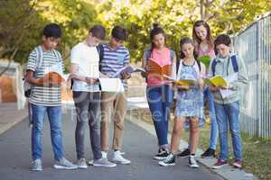 School kids reading books on road in campus