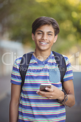 Schoolboy using mobile phone in campus at school