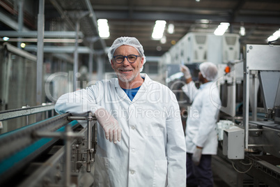 Smiling factory worker standing next to production line