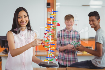 Smiling schoolgirl studying molecule model in laboratory