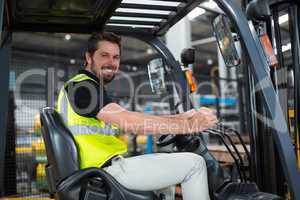 Portrait of smiling factory worker driving forklift