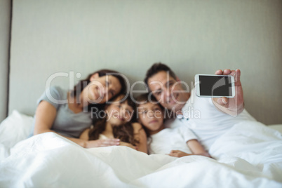 Parents and kids taking a selfie on bed