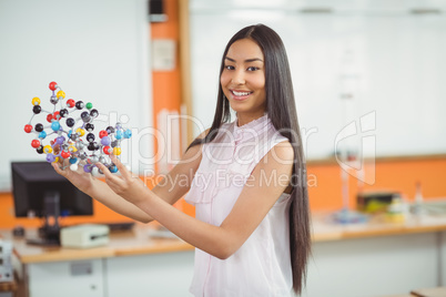 Portrait of happy schoolgirl experimenting molecule model in laboratory