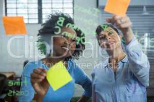 Female graphic designer pointing to the sticky notes on the glass