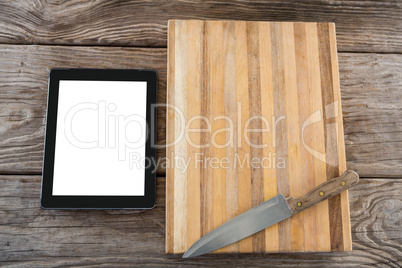 Digital tablet, knife and wooden tray against wooden background