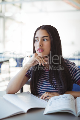 Thoughtful schoolgirl sitting in classroom