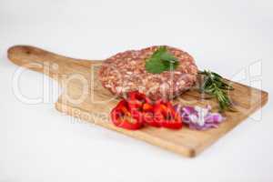 Beef patty and ingredients on wooden tray