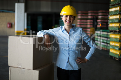 Smiling female factory worker standing with hand on hip in factory