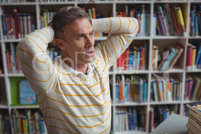 Tensed school teacher sitting in library