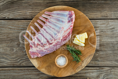 Beef ribs rack, rosemary herb, salt and lemon on wooden tray against wooden background