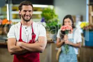 Smiling florist standing in florist shop with arms crossed