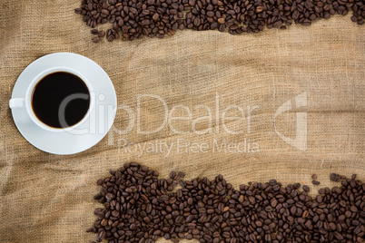 Coffee cup with coffee beans arranged on sack