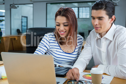 Man and woman working on laptop at desk