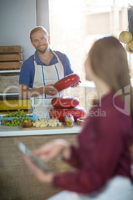 Salesman holding gouda cheese and interacting with costumer
